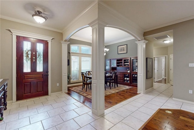 entrance foyer featuring decorative columns, light tile patterned floors, arched walkways, ornamental molding, and baseboards