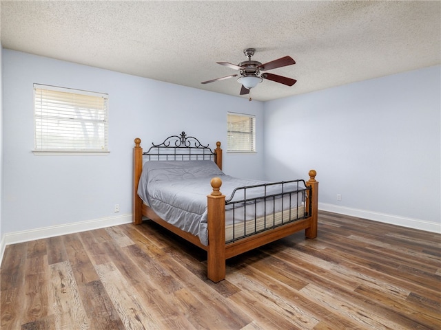 bedroom with hardwood / wood-style flooring, ceiling fan, and a textured ceiling