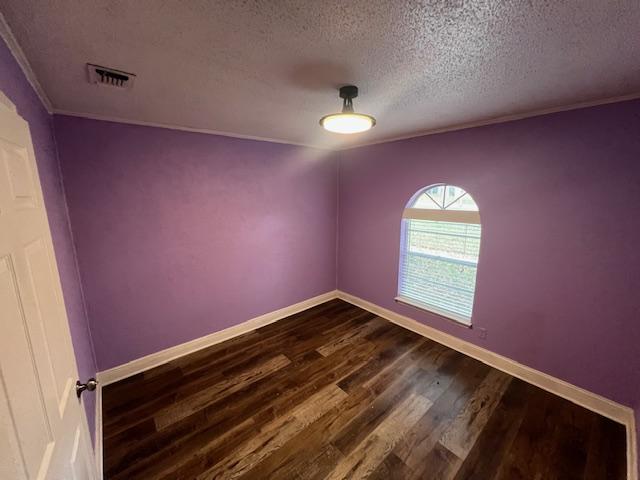 spare room with a textured ceiling and dark wood-type flooring