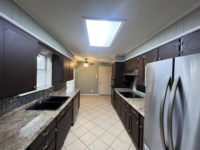 kitchen featuring ceiling fan, sink, black appliances, and light stone counters