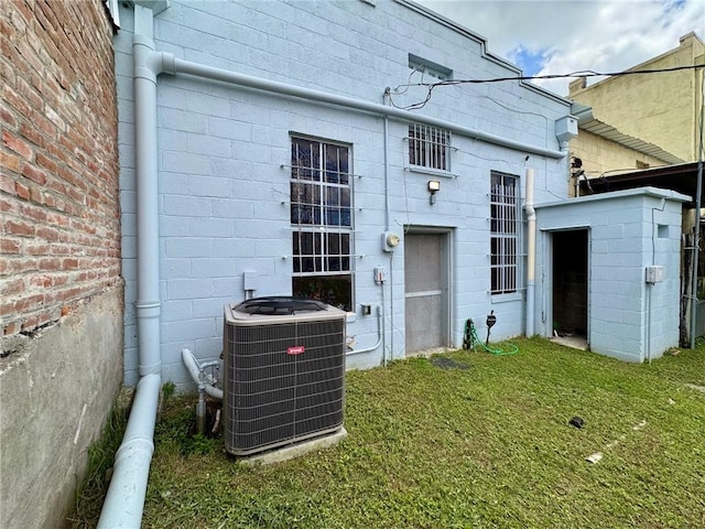 517 S Main St, Calvert, TX 77837 - back of house featuring cooling unit, concrete block siding, and a lawn