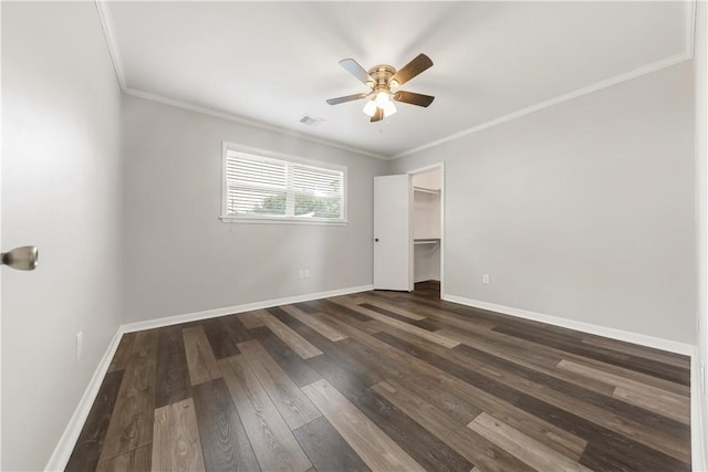 3614 Oak Ridge Dr, Bryan, TX 77802 - unfurnished bedroom featuring dark wood-style floors, crown molding, ceiling fan, and a walk in closet