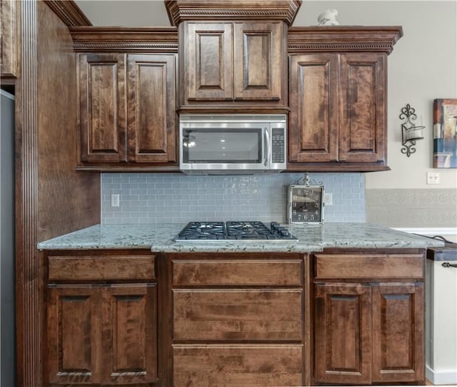 kitchen with appliances with stainless steel finishes, light stone counters, and decorative backsplash