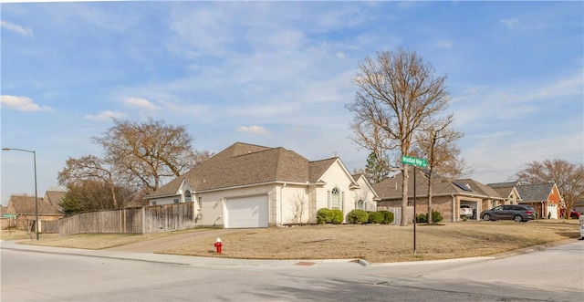 view of front of property featuring a garage, concrete driveway, fence, and a residential view