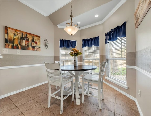 dining area with lofted ceiling, a wainscoted wall, crown molding, and tile patterned floors