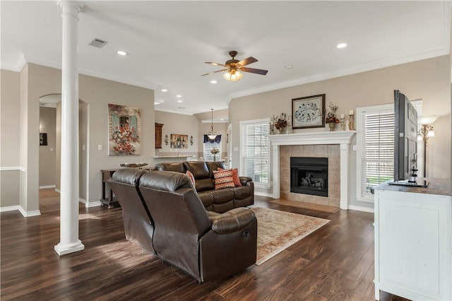 living area with decorative columns, visible vents, ceiling fan, ornamental molding, and dark wood-style flooring