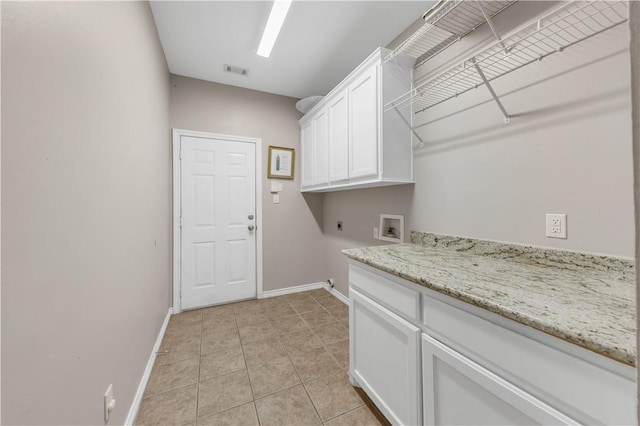 clothes washing area featuring washer hookup, cabinet space, light tile patterned flooring, electric dryer hookup, and baseboards