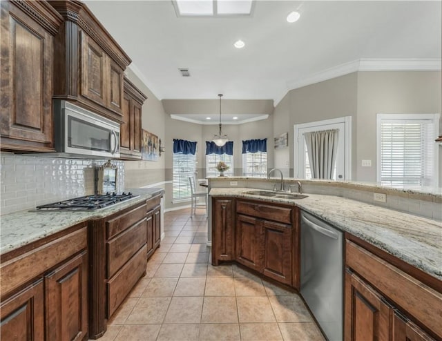 kitchen featuring crown molding, stainless steel appliances, hanging light fixtures, backsplash, and a sink