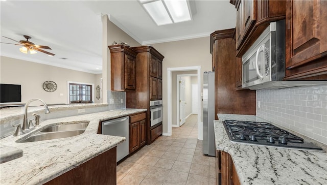 kitchen with light stone counters, crown molding, appliances with stainless steel finishes, light tile patterned flooring, and a sink