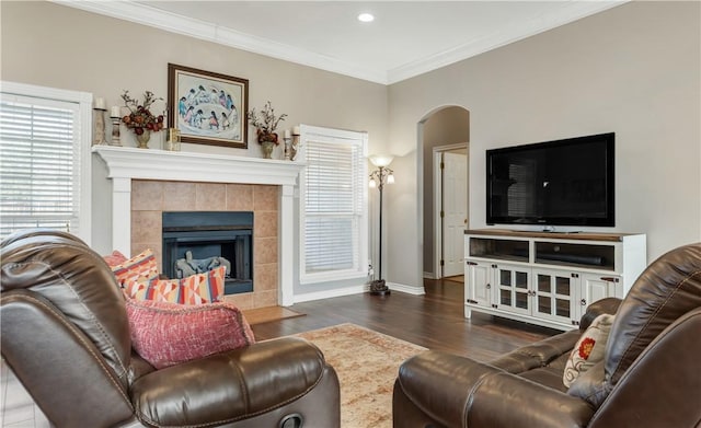 living area with arched walkways, a fireplace, baseboards, dark wood-style floors, and crown molding