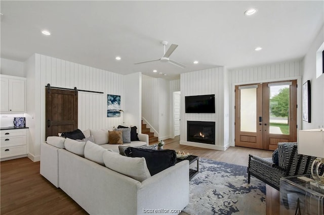 living room featuring a barn door, light hardwood / wood-style floors, and ceiling fan