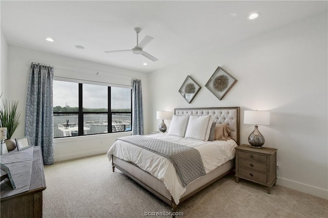 bedroom featuring ceiling fan, a water view, and light colored carpet