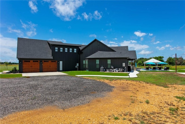 1981 County Road 202, Caldwell, TX 77836 - view of front of home featuring board and batten siding, a front lawn, gravel driveway, an attached garage, and a gazebo