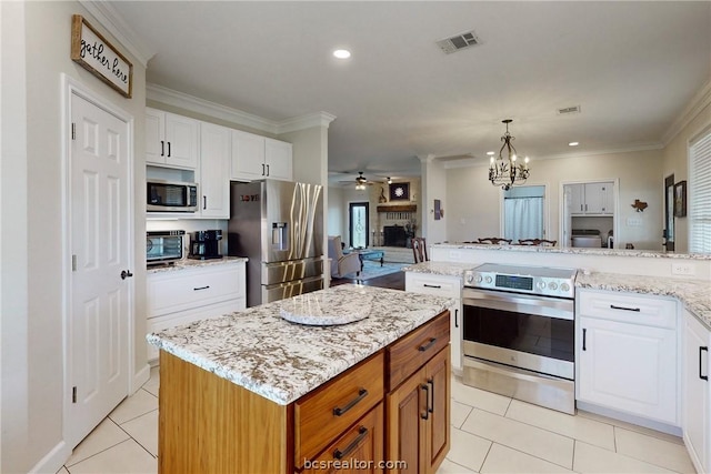 kitchen with a center island, light tile patterned floors, ornamental molding, white cabinetry, and stainless steel appliances