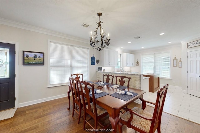 dining area with hardwood / wood-style flooring, crown molding, and a notable chandelier