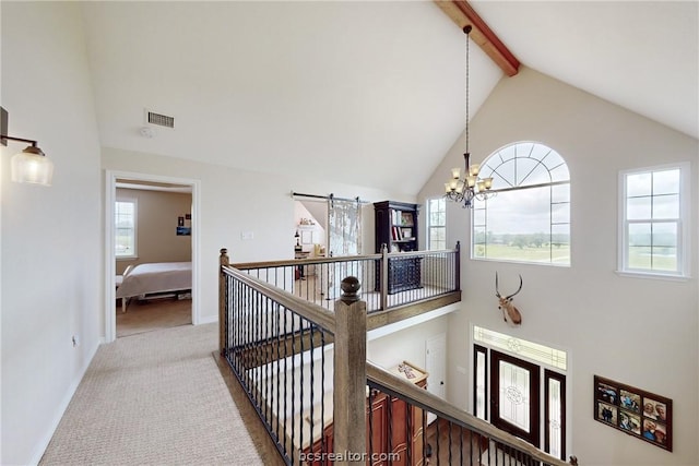 hall featuring lofted ceiling with beams, a barn door, carpet floors, and an inviting chandelier