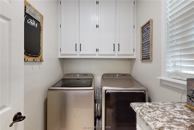 laundry room featuring separate washer and dryer and cabinets