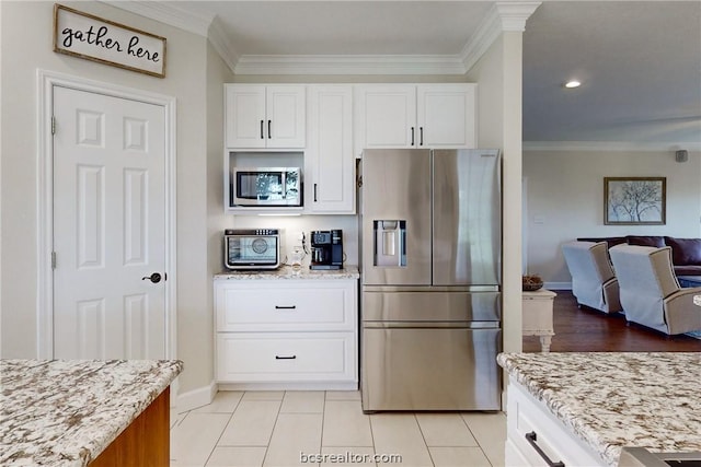 kitchen featuring white cabinets, stainless steel fridge, light tile patterned floors, and light stone counters