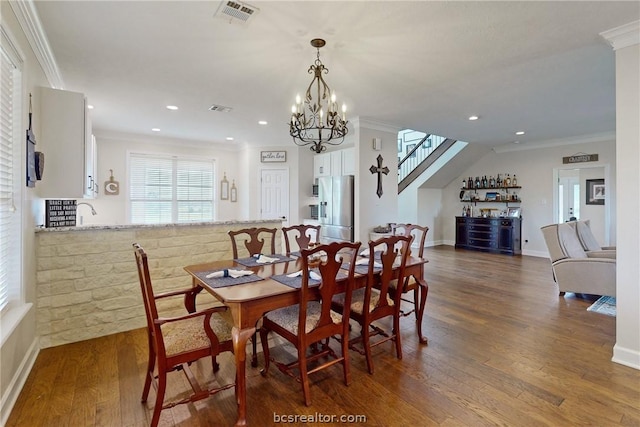 dining room featuring a chandelier, bar area, dark hardwood / wood-style floors, and ornamental molding