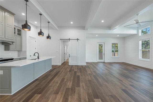 kitchen featuring sink, pendant lighting, beamed ceiling, gray cabinetry, and a barn door