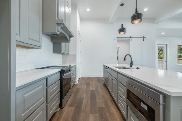 kitchen with stainless steel appliances, decorative light fixtures, gray cabinets, a barn door, and sink