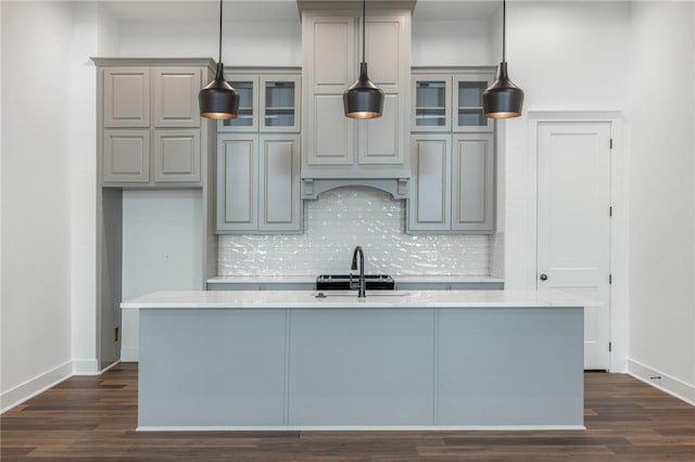 kitchen with sink, backsplash, a kitchen island with sink, and decorative light fixtures