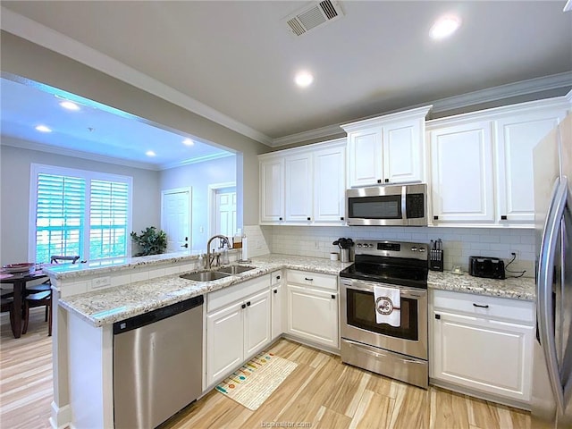 801 Luther St W Unit 1407, College Station, TX 77840 - kitchen with stainless steel appliances, a sink, decorative backsplash, white cabinets, and a peninsula