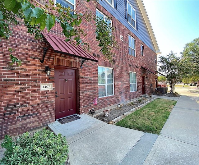 801 Luther St W Unit 1407, College Station, TX 77840 - property entrance featuring a standing seam roof, central AC, metal roof, and brick siding