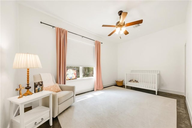 bedroom featuring visible vents, a crib, baseboards, and a ceiling fan