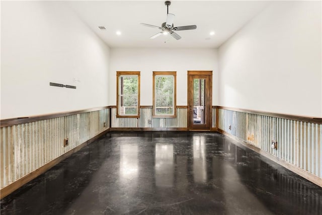 spare room with a ceiling fan, a wainscoted wall, and visible vents