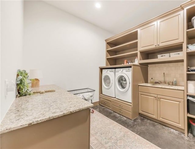 laundry room featuring washing machine and clothes dryer, cabinet space, and a sink