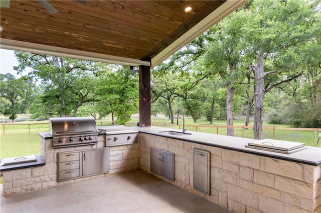 view of patio featuring exterior kitchen, grilling area, a sink, and fence