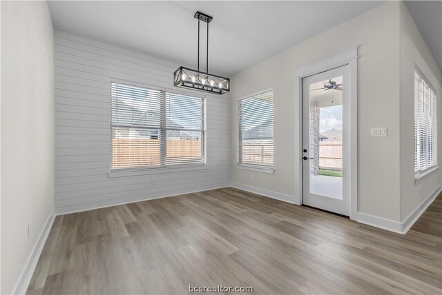 unfurnished dining area featuring hardwood / wood-style floors and wood walls