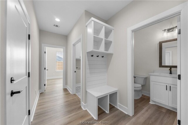 mudroom with sink and light hardwood / wood-style flooring