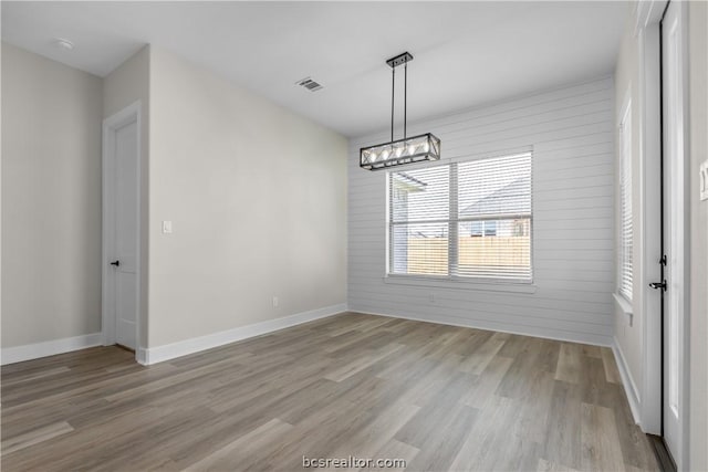 unfurnished dining area with light hardwood / wood-style flooring and wooden walls