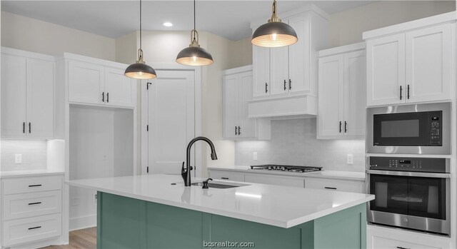 kitchen featuring backsplash, stainless steel appliances, sink, decorative light fixtures, and white cabinets