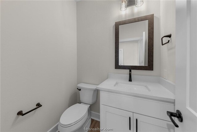 bathroom with hardwood / wood-style flooring, vanity, and toilet