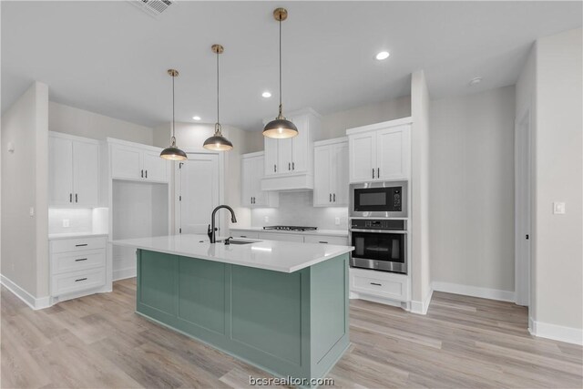 kitchen featuring white cabinets, sink, light wood-type flooring, an island with sink, and stainless steel appliances