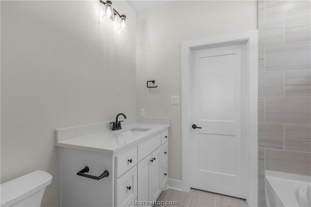 bathroom featuring a bathing tub, vanity, and toilet