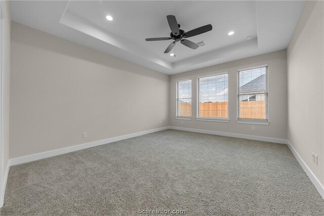 unfurnished room with ceiling fan, carpet floors, and a tray ceiling