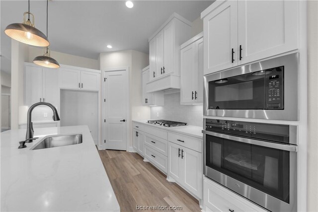 kitchen with white cabinetry, sink, light wood-type flooring, and appliances with stainless steel finishes