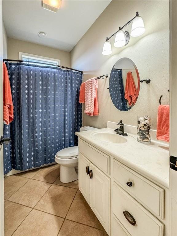 bathroom with tile patterned flooring, vanity, toilet, and walk in shower