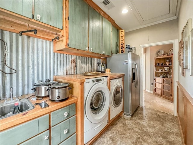 laundry room featuring washing machine and dryer, crown molding, and sink