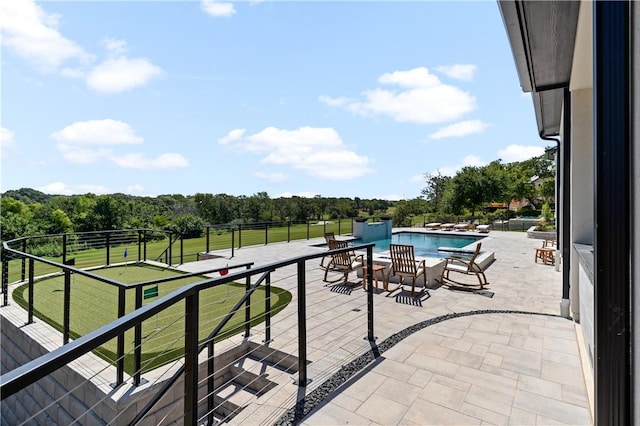 view of patio featuring a balcony and a fenced in pool