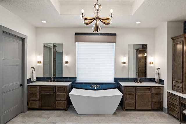 bathroom with vanity, a washtub, a chandelier, and a textured ceiling