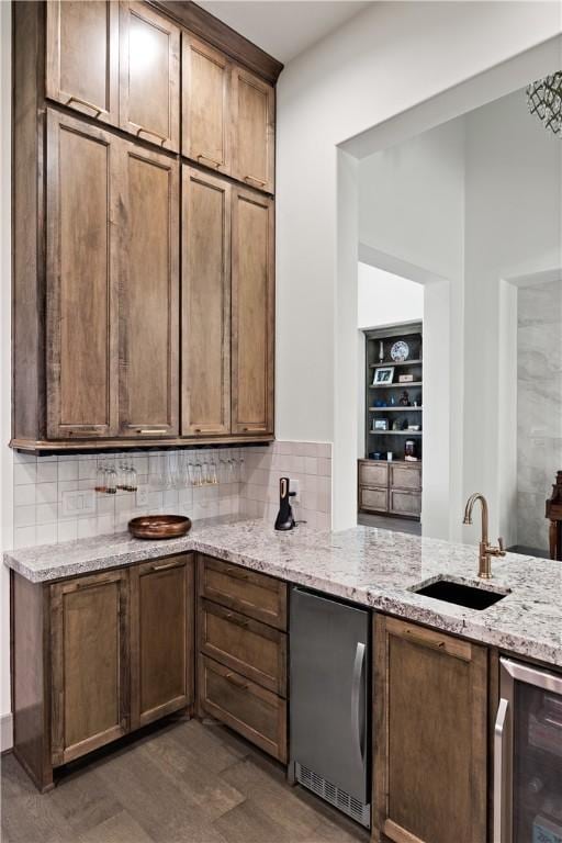 bar with light stone counters, wine cooler, backsplash, fridge, and sink