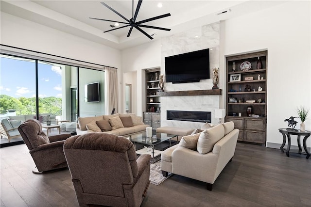 living room featuring dark hardwood / wood-style flooring, a chandelier, a high end fireplace, and built in shelves