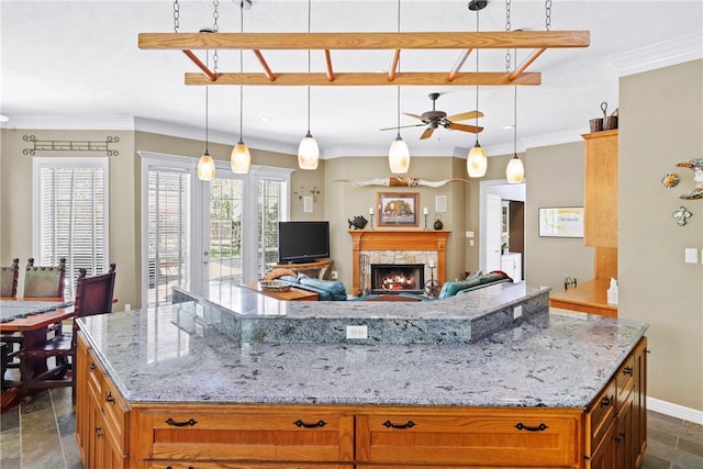 4304 Newcastle Ct, Bryan, TX 77802 - kitchen featuring stone finish floor, ceiling fan, a large island, a fireplace, and light stone counters