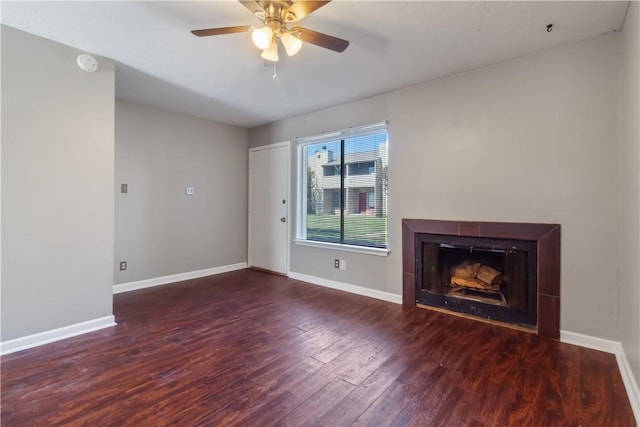 unfurnished living room with ceiling fan, a fireplace, and dark wood-type flooring