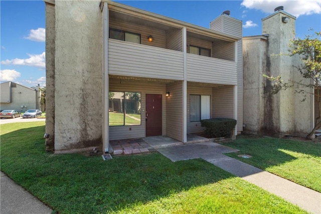 view of front facade featuring a front yard and a balcony